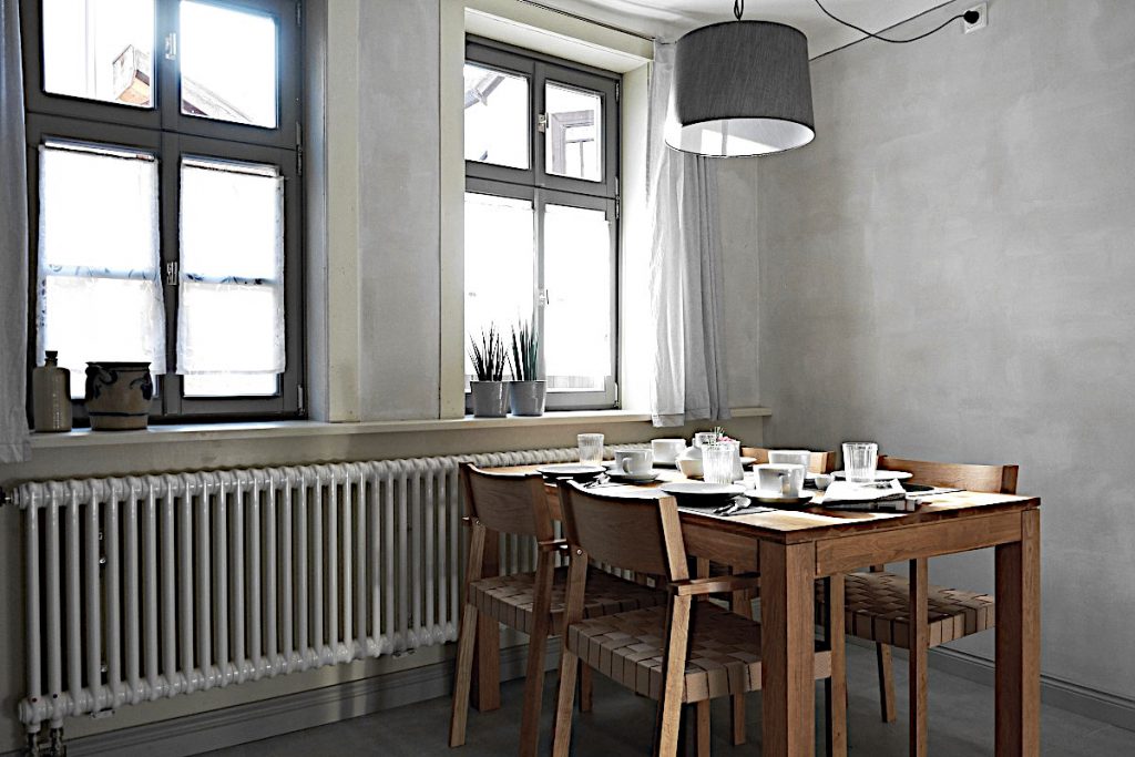 Brauner Holz - Esstisch in der Küche eingedeckt mit weißem Geschirr.