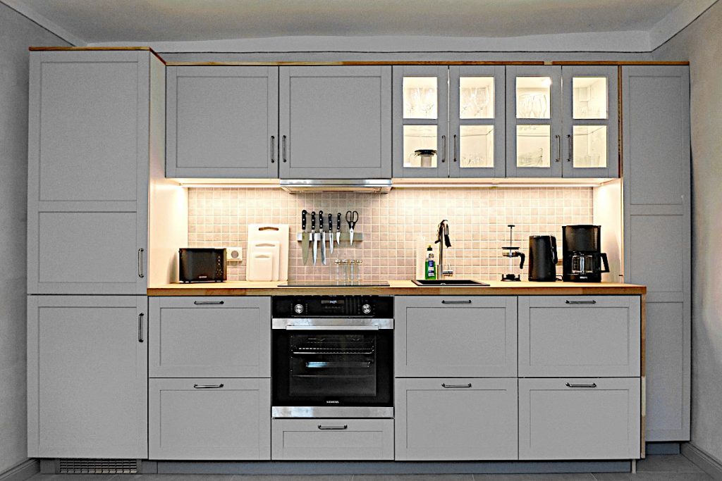 Graue Küchenzeile mit Küchengeräten und Beleuchtung.