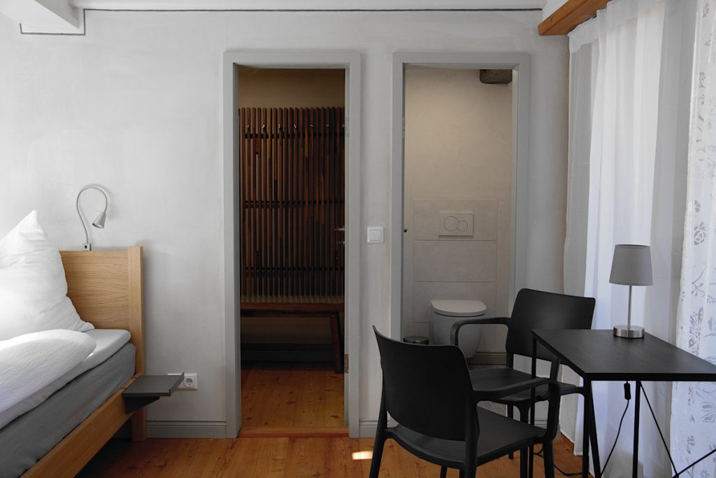 Schlafzimmer mit kleinem Schreibtisch, WC und begehbarem Schrank.