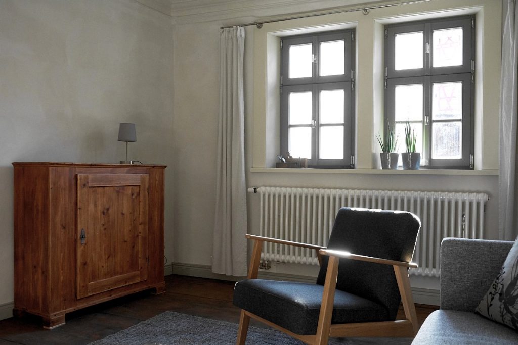 Grau gestrichenes Wohnzimmer mit braunem kleinen Bücherschrank aus Holz.