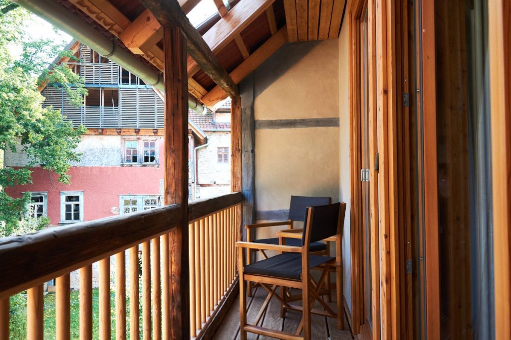 Laubengang am kleinen Schlafzimmer mit zwei Holzstühlen.