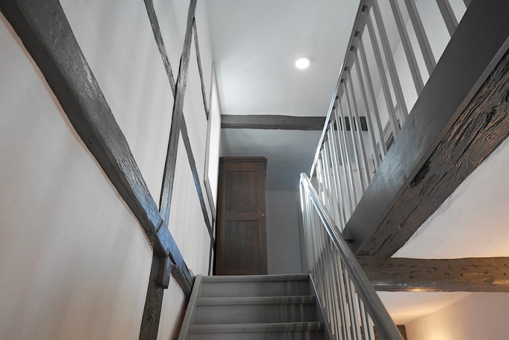 Treppenraum mit weißen Wänden, Holzteile unterschiedlich grau gestrichen.