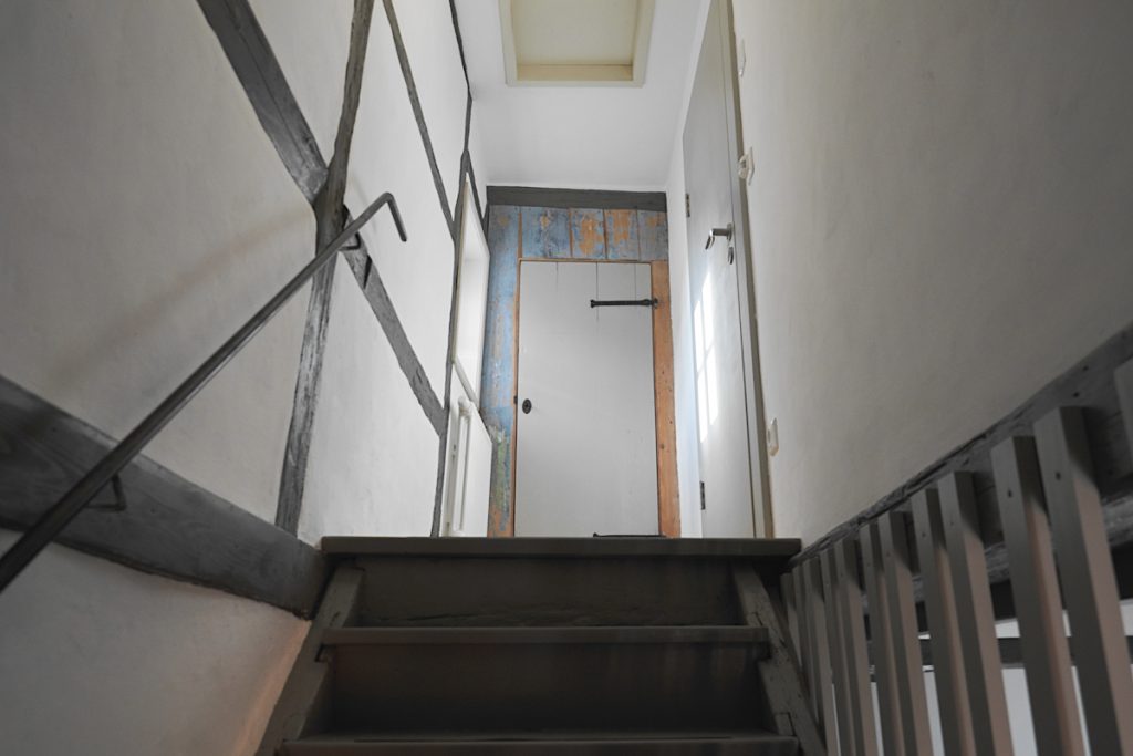 Treppenraum mit weißen Wänden, Holzteile unterschiedlich grau gestrichen.