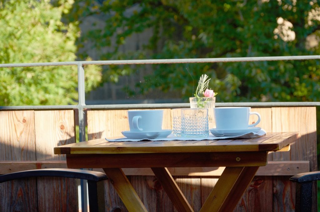 Ferienhaus Kontakt für uns. Weiße Kaffeetassen auf braunem Holztisch auf der Dachterrasse.