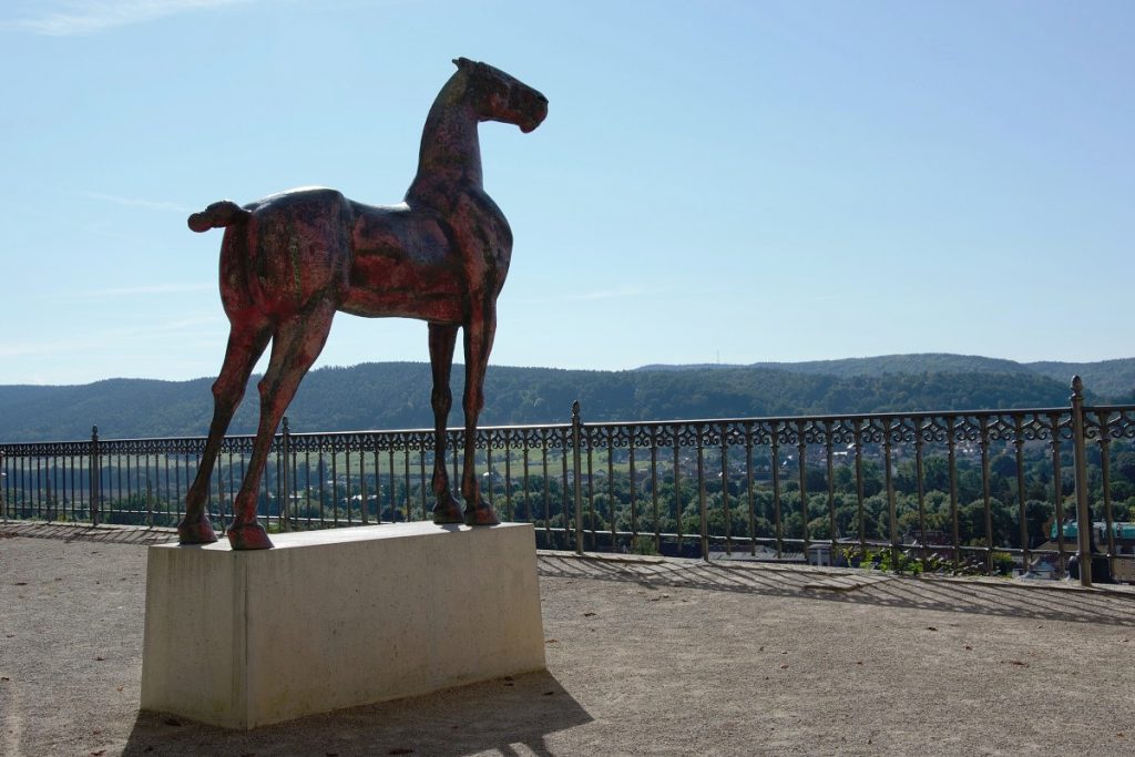 Pferdeskulptur "Roter Huzule" auf der Heidecksburg Rudolstadt vor blauem Himmel im Sonnenschein.