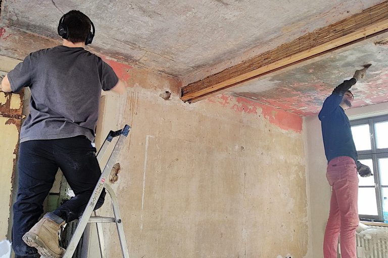 Ferienhaus Mittelgasse 15, Reinigung alter Putzflächen mit Spachtel und Schwamm vor Überarbeitung.