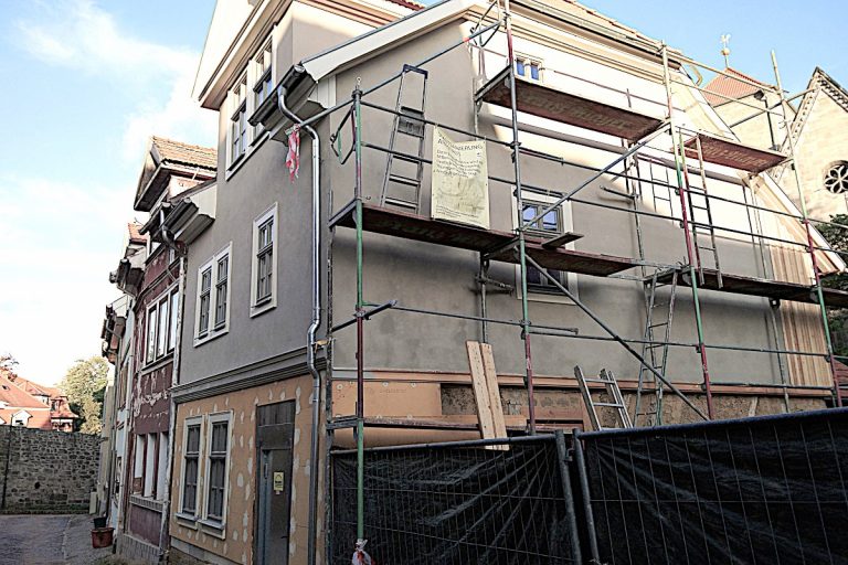 Ferienhaus Mittelgasse 15, teilweise fertiggestellte Fassade mit unterschiedlichen Grautönen und grau gestrichenen Sprossenfenstern.