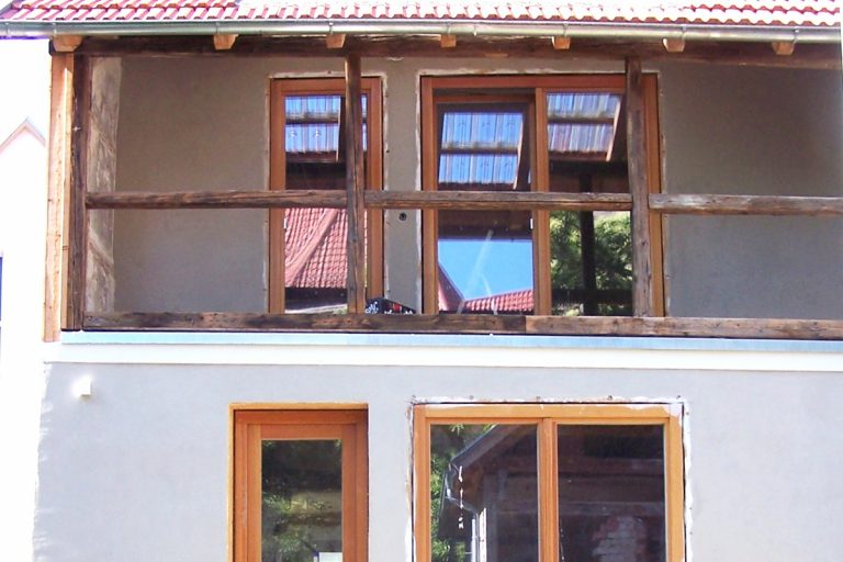 Naturfarbene Lärchenholz - Fenstertüren an Gebäuderückseite.